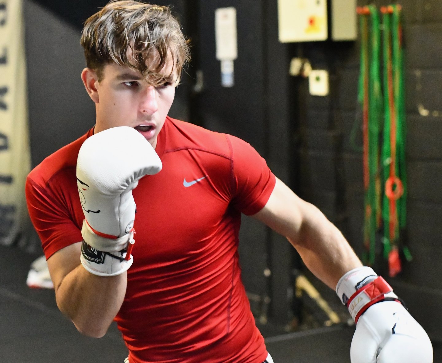Reece boxing in red training kit and white gloves
